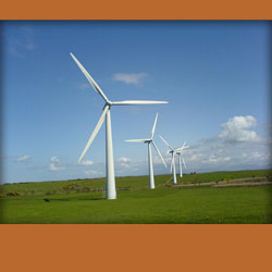 A row of wind turbines spinning in an open green field